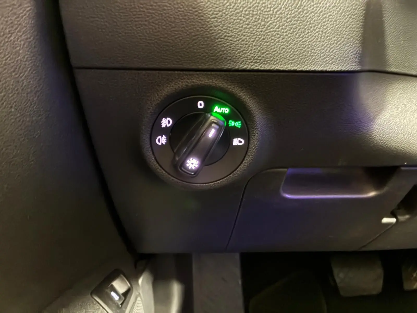 Gros plan sur le sélecteur de phares allumés en mode automatique dans l’habitacle noir du Skoda Karoq 2023.