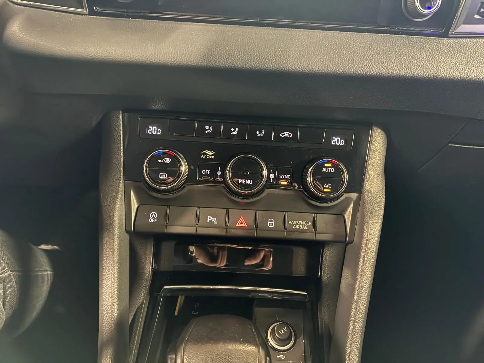 Vue rapprochée du tableau de bord noir du Skoda Karoq 2023, mettant en valeur la console de climatisation automatique et les commandes.