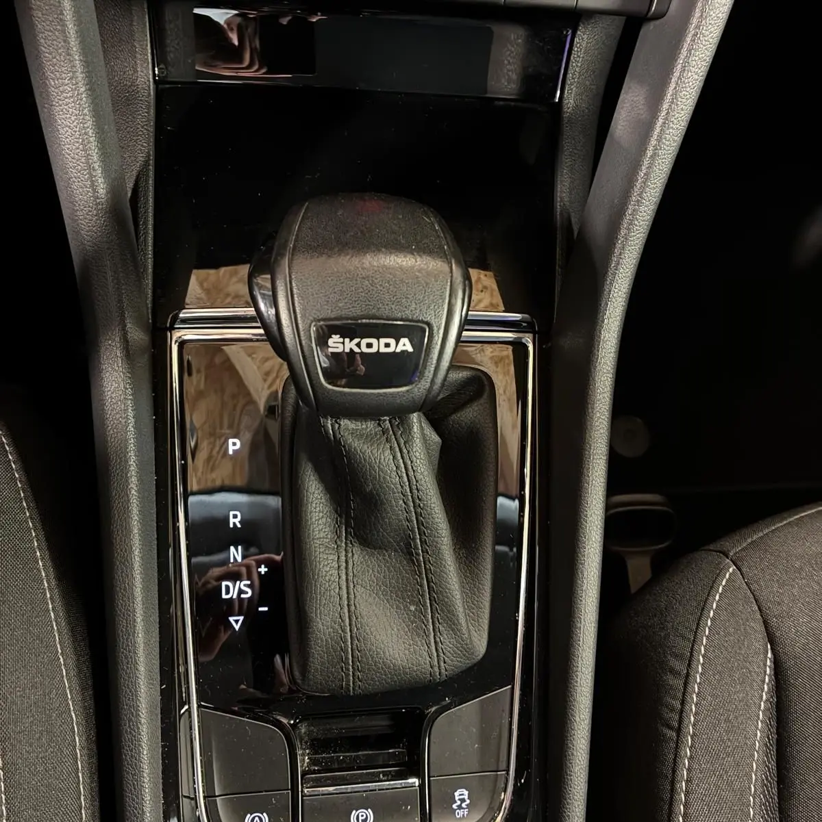 Gros plan sur la console centrale noire du Skoda Karoq 2023, mettant en valeur le levier de vitesses automatique marqué ŠKODA.