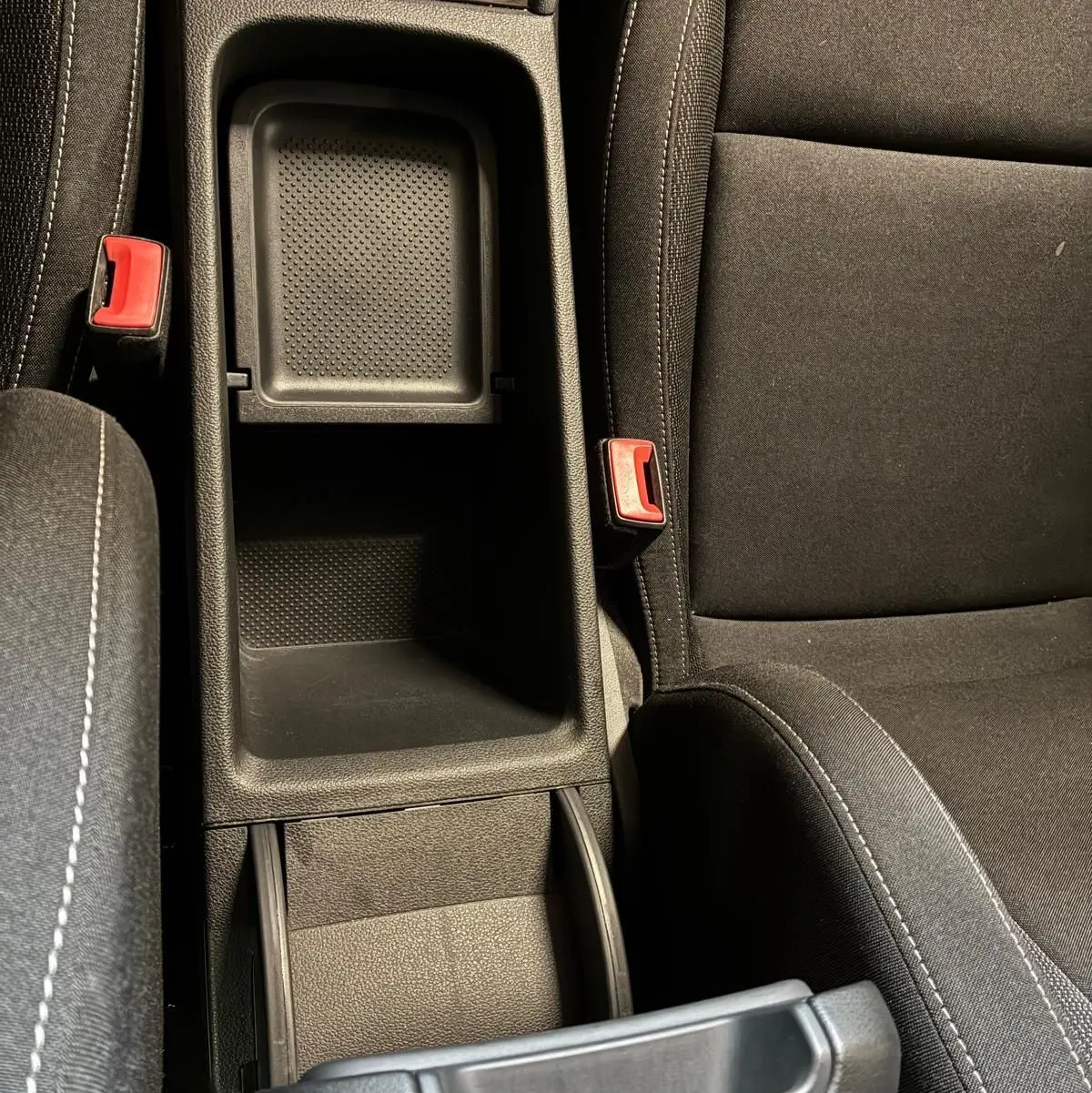 Vue plongeante sur le rangement central noir et les sièges en tissu noir de la Skoda Karoq 2023 version Business.