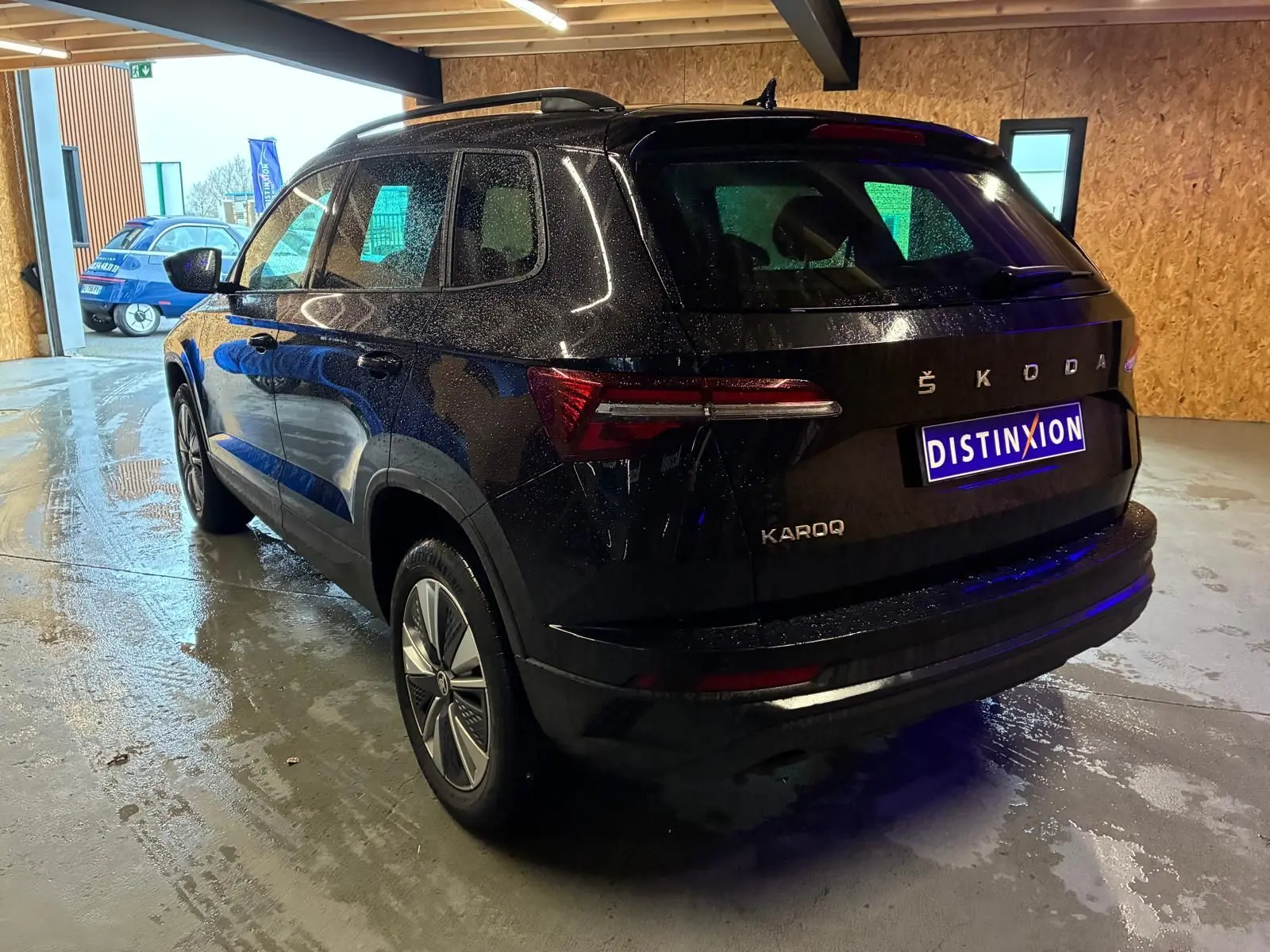 Vue 3/4 arrière droite d'un Skoda Karoq noir 2023 avec carrosserie brillante et feux arrière LED dans un garage.