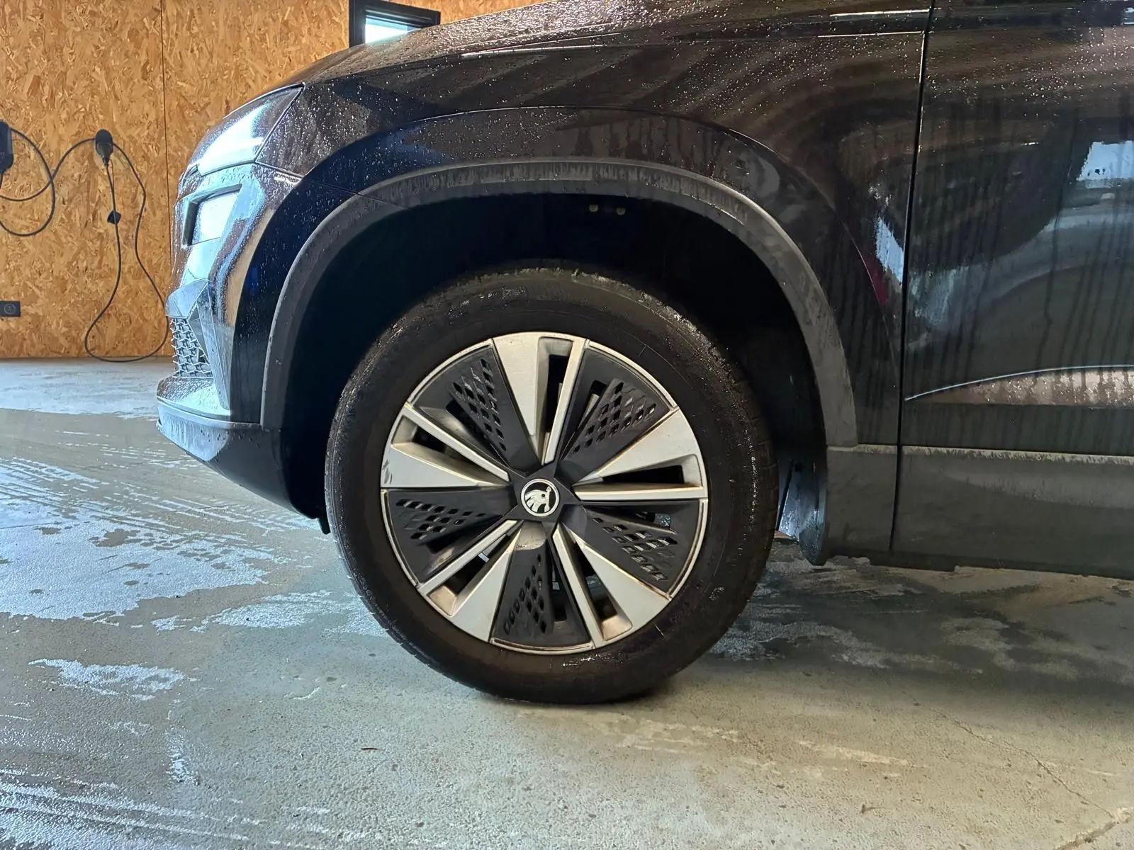 Gros plan sur la roue avant gauche d'un Skoda Karoq noir 2023, mettant en valeur la jante au design moderne.