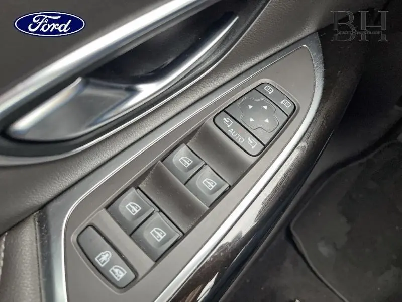 Gros plan sur les commandes de lève-vitres côté conducteur d'un Renault Espace noir étoilé, avec poignée argentée.