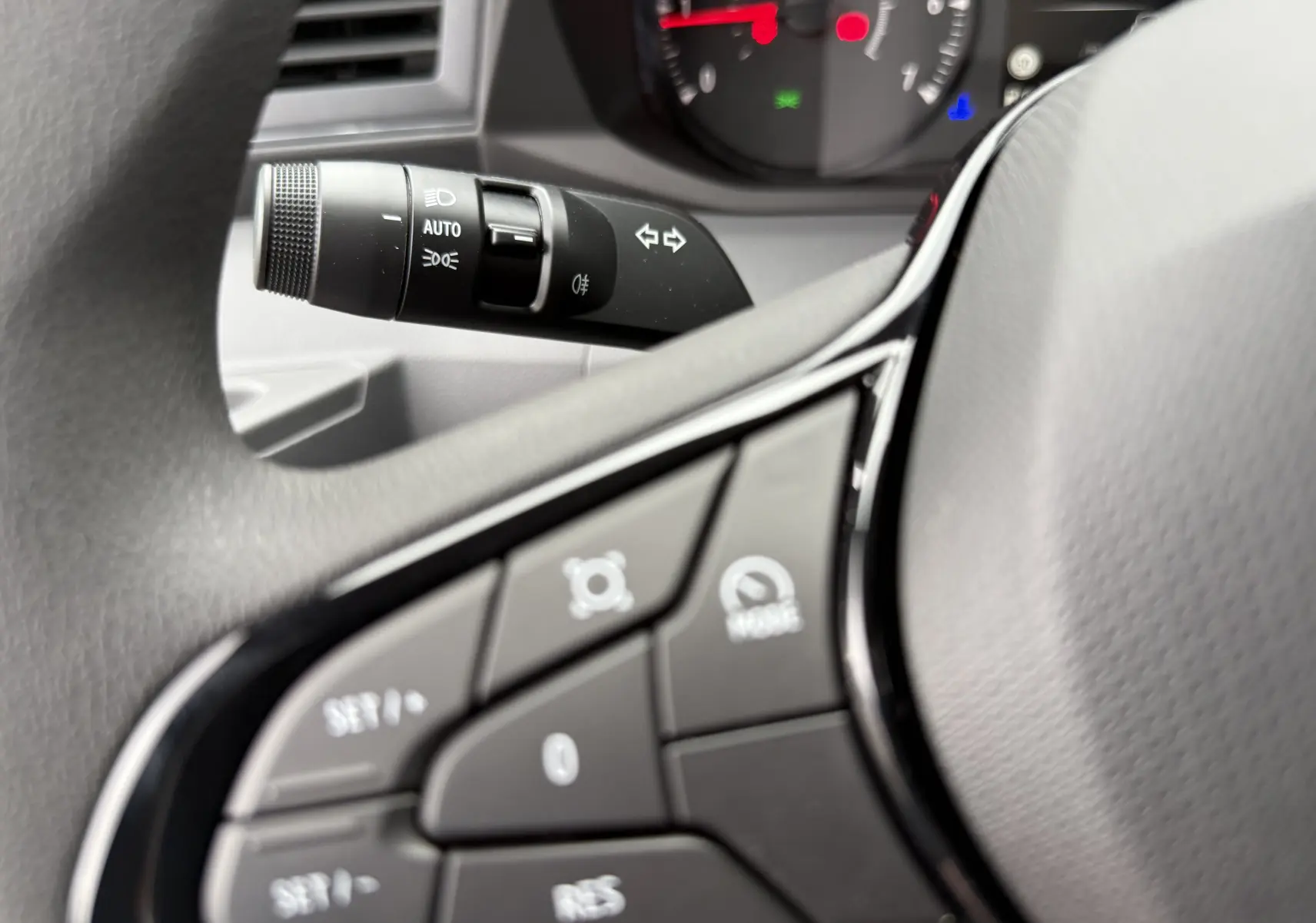 Gros plan sur les commandes au volant et le commodo des phares du Renault Master 2024, intérieur gris.
