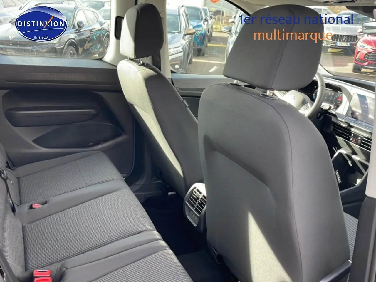 Vue intérieure arrière du Volkswagen Caddy 2.0 TDI 122 DSG7 2025 en tissu noir titane, montrant les sièges et la console centrale.