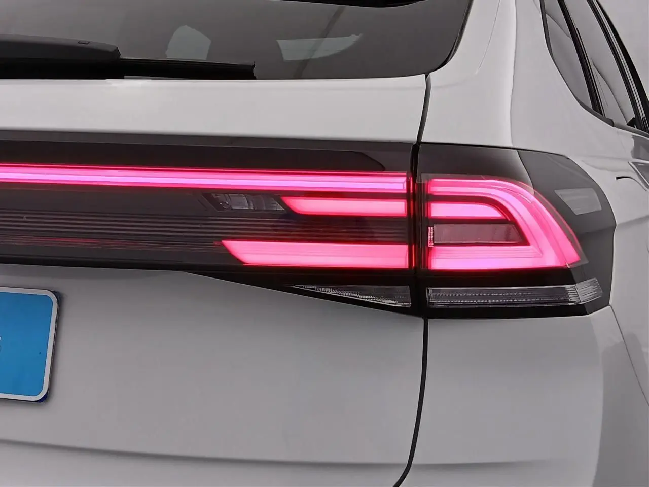 Gros plan sur le feu arrière droit allumé du Volkswagen Taigo blanc pur avec toit noir, version R-Line 2025.