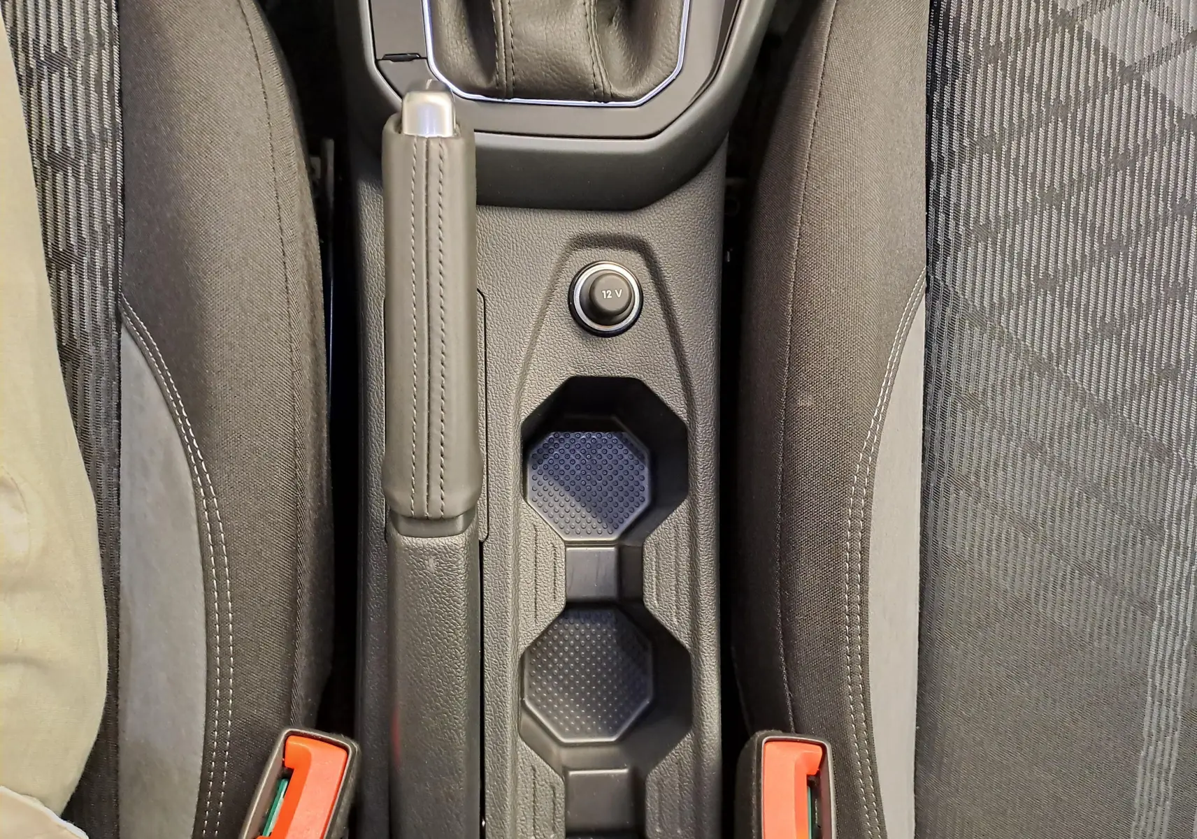 Vue plongeante sur la console centrale noire entre les sièges avant gris foncé du Volkswagen Taigo 2025.
