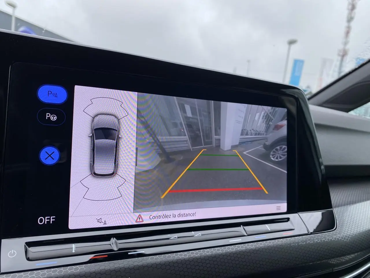 Écran de caméra de recul et assistance au stationnement dans l'habitacle d'une Volkswagen Golf blanche 2023.