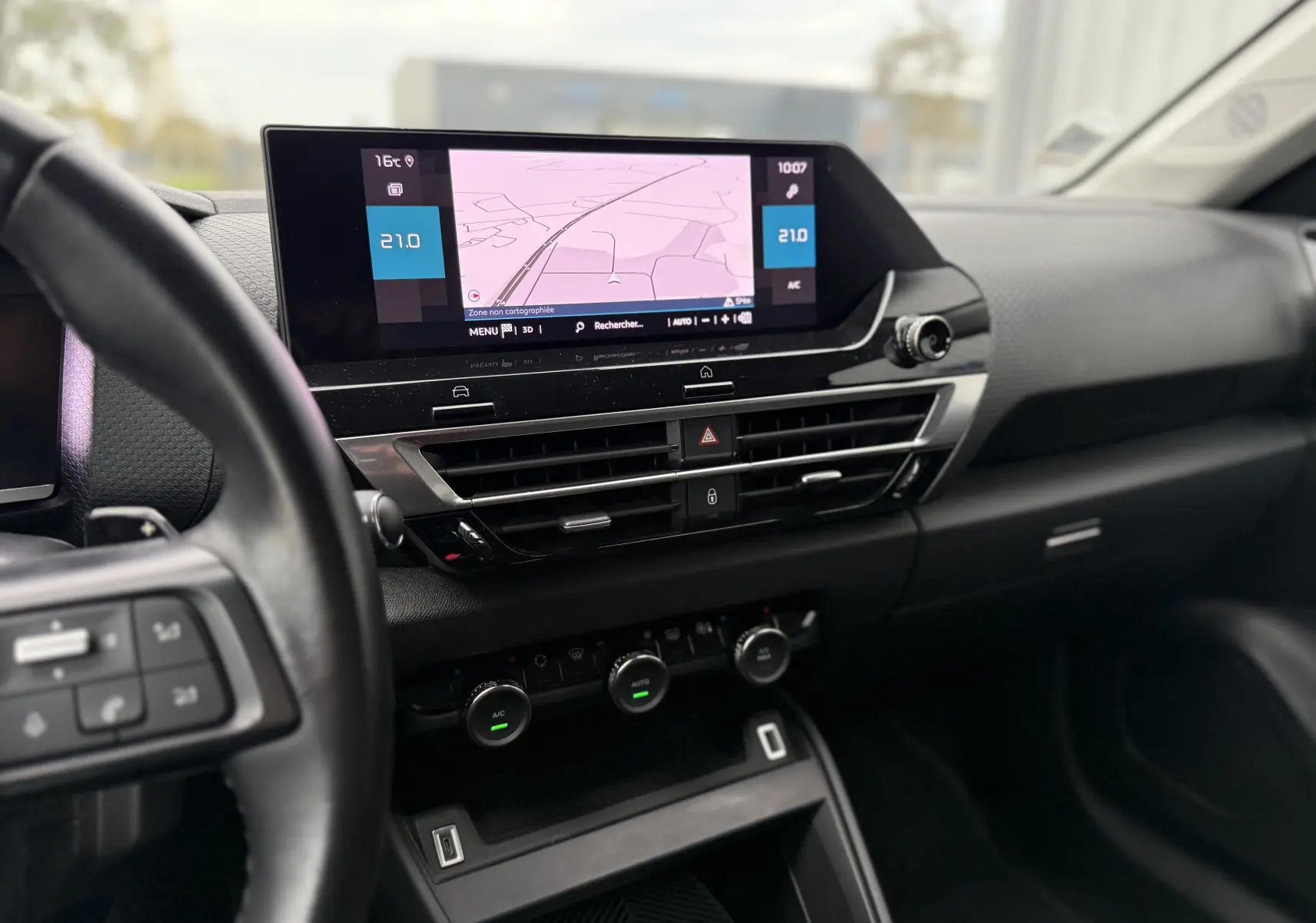 Tableau de bord noir de la Citroën C4 2022 avec écran tactile central affichant la navigation et commandes climatiques.