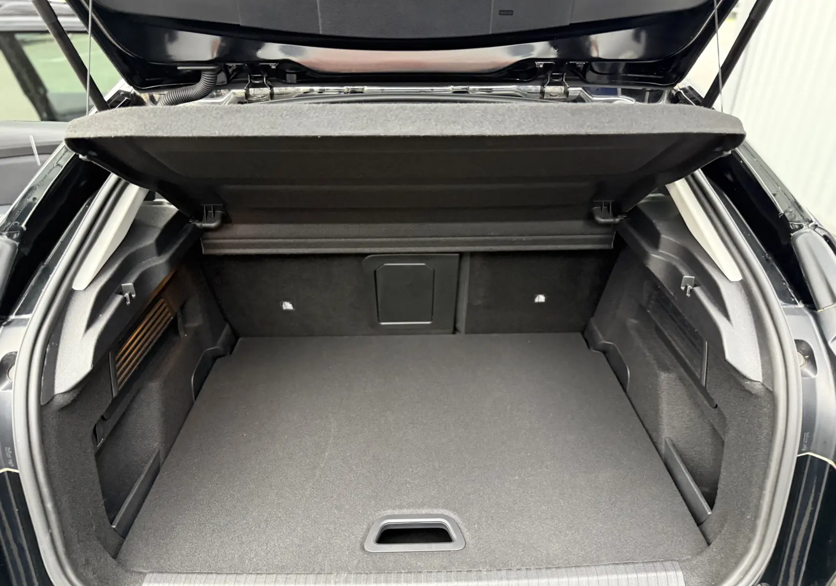 Coffre ouvert vu de l'arrière d'une Citroën C4 noire 2022, montrant un espace de chargement propre et spacieux.