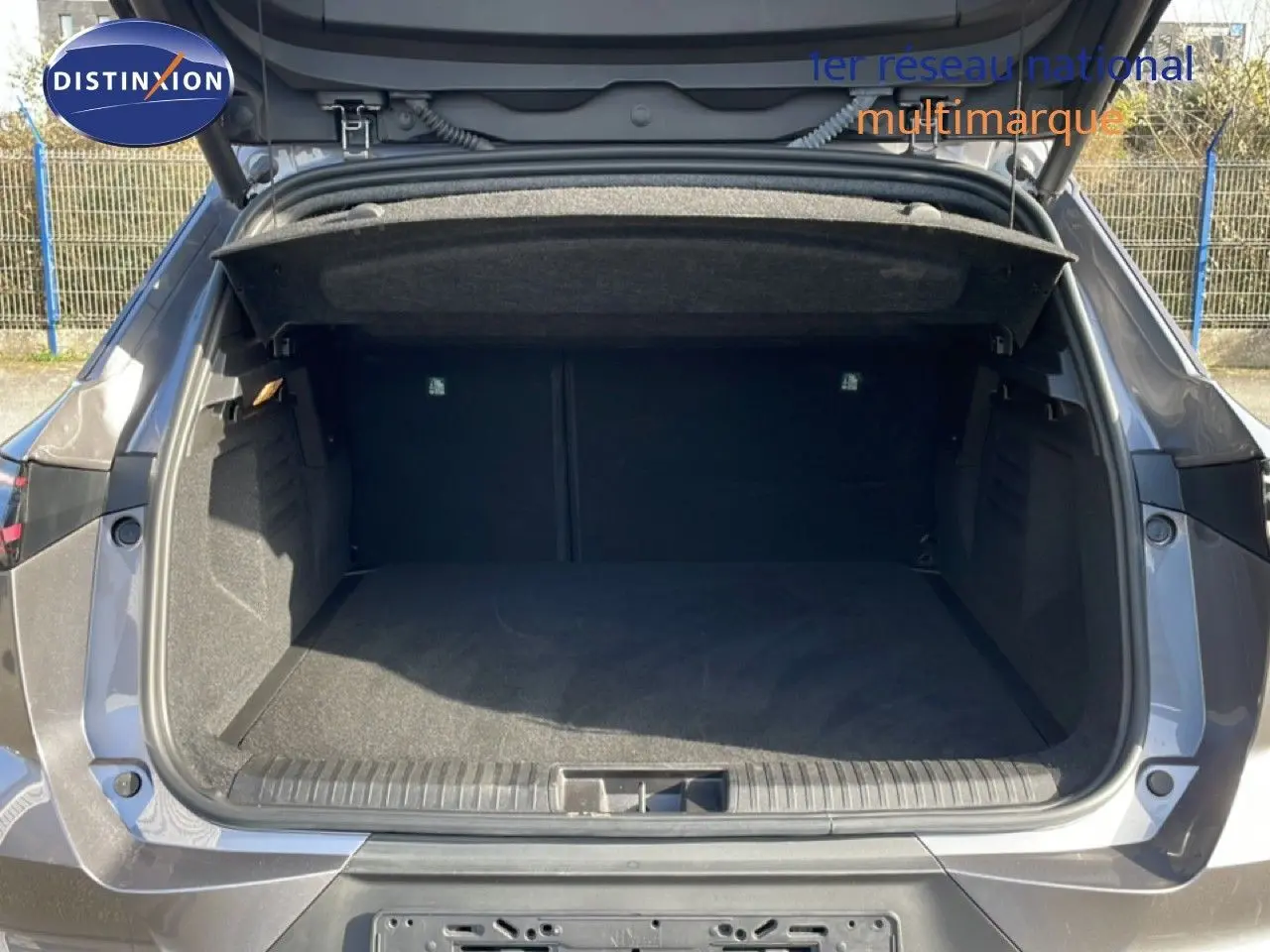 Coffre ouvert vu de l’arrière d’une Renault Symbioz gris cassiopée métal, montrant un espace de chargement spacieux et propre.
