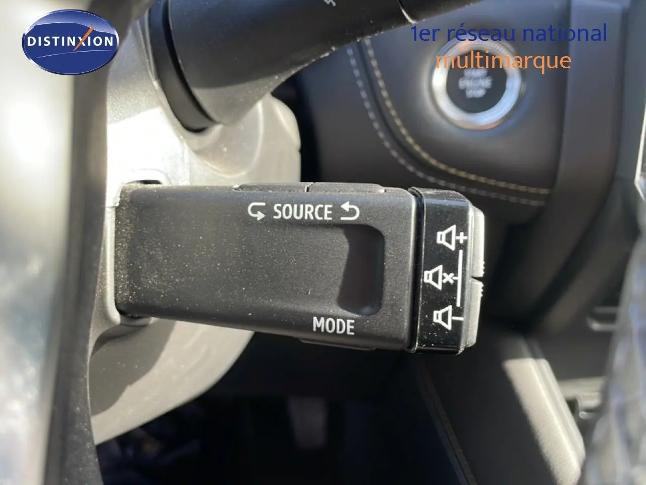 Gros plan sur la commande au volant avec boutons source et mode dans l’habitacle noir du Renault Symbioz gris cassiopée.