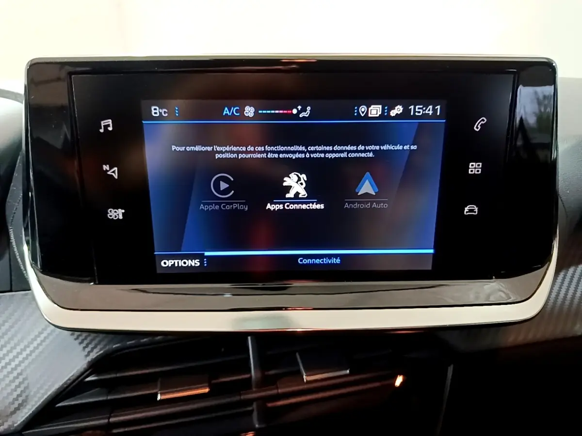 Écran tactile central du tableau de bord du Peugeot 208 blanc, affichant les options Apple CarPlay et Android Auto.