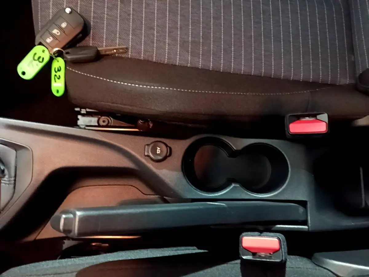 Vue rapprochée de la console centrale intérieure avec frein à main, porte-gobelets et clé de Peugeot 208 blanche.