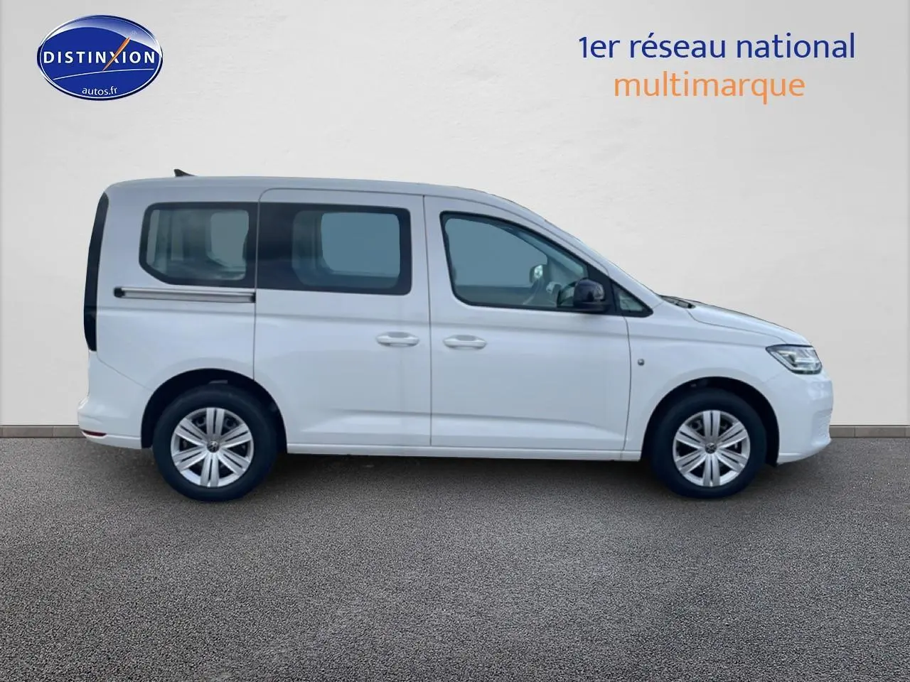 Vue de profil côté gauche d'un Volkswagen Caddy blanc 2025 avec vitres teintées et barres de toit visibles.