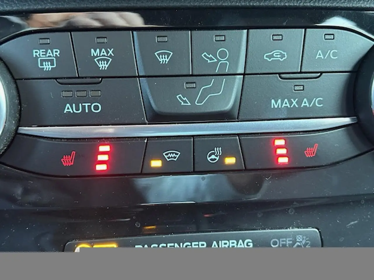 Gros plan sur la console centrale du Ford Puma gris Magnetic 2023, montrant les commandes de climatisation et sièges chauffants activés.