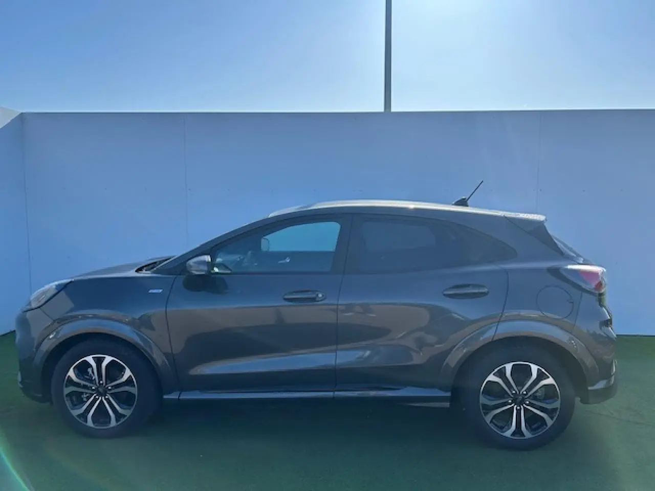 Vue de profil côté gauche d'un Ford Puma gris Magnetic avec jantes alliage 17 pouces et toit blanc.
