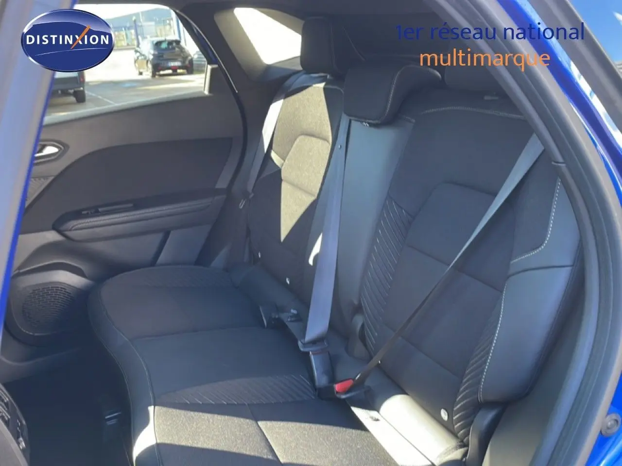 Vue intérieure côté droit des sièges arrière noirs du Renault Symbioz bleu iron metal, avec ceinture de sécurité attachée.