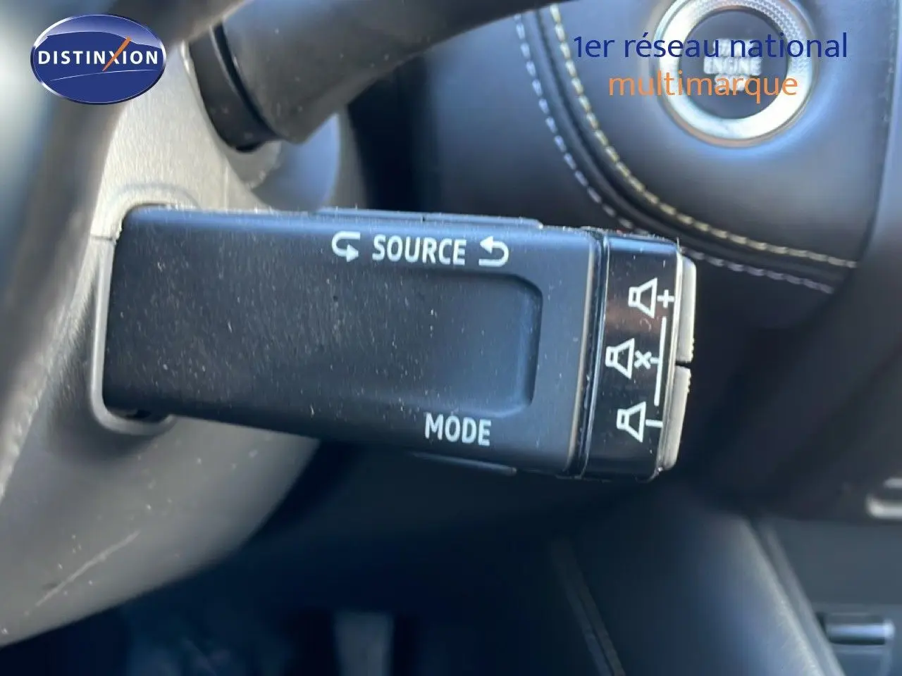 Gros plan sur la commande au volant noire avec inscriptions blanches dans l'habitacle noir du Renault Symbioz bleu iron metal.
