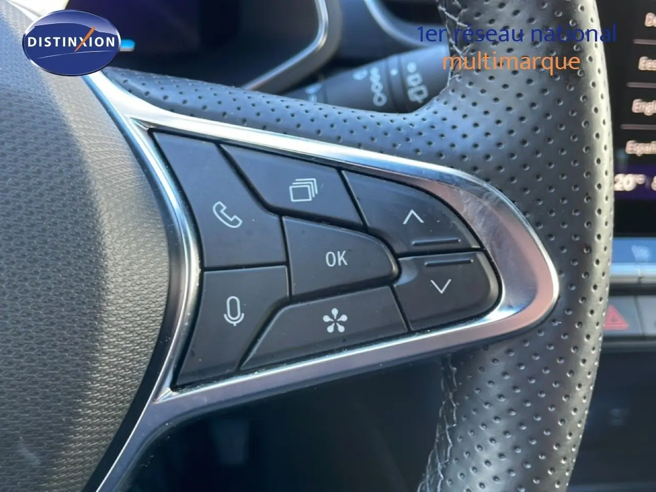 Gros plan sur les commandes gauche du volant perforé d’une Renault Symbioz bleu Iron Metal, avec boutons multifonctions.