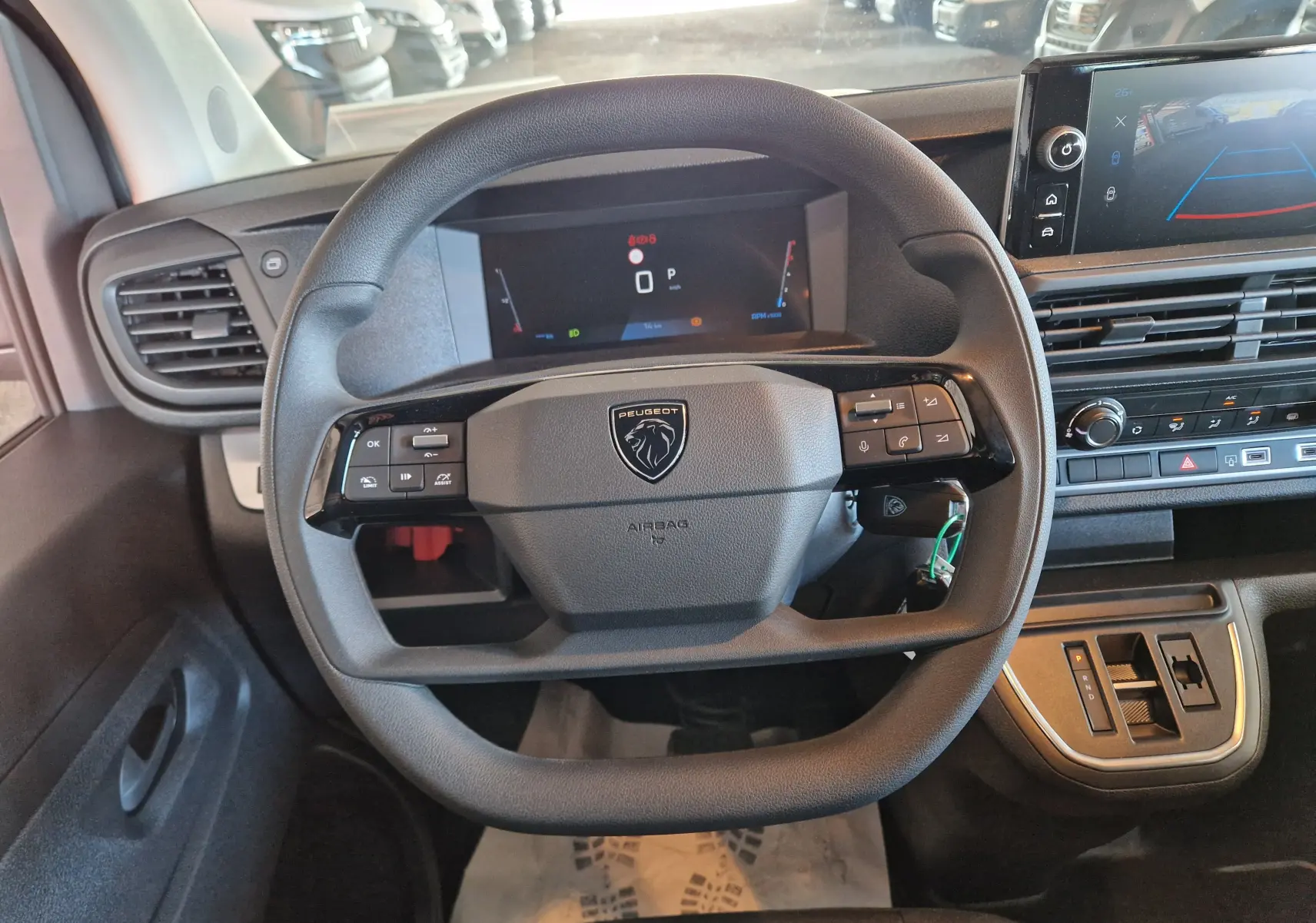 Vue rapprochée du volant noir du Peugeot Expert Cabine Approfondie gris titane, avec tableau de bord numérique et écran tactile.