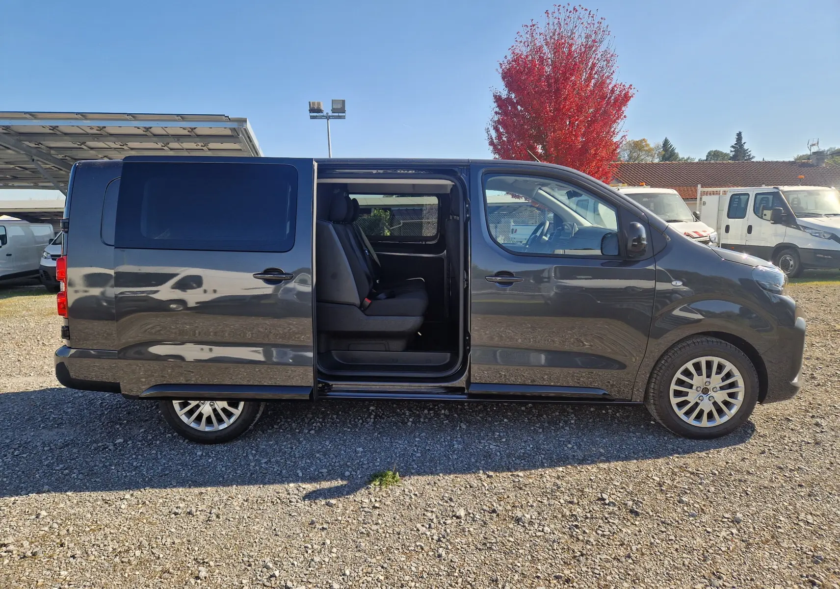 Profil côté droit du Peugeot Expert Cabine Approfondie gris titane 2025 avec porte coulissante ouverte révélant les sièges passagers.