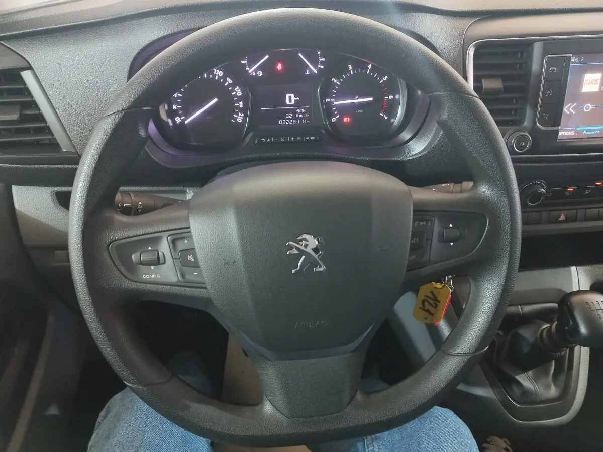 Vue rapprochée du volant noir et du tableau de bord digital du Peugeot Traveller 2021 avec levier de vitesses manuel.