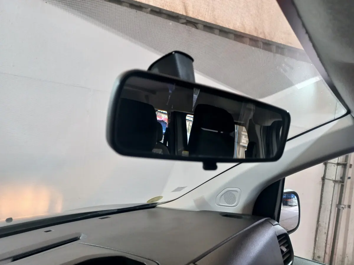 Vue intérieure du rétroviseur central du Peugeot Traveller gris clair, montrant partiellement les sièges arrière et le tableau de bord.