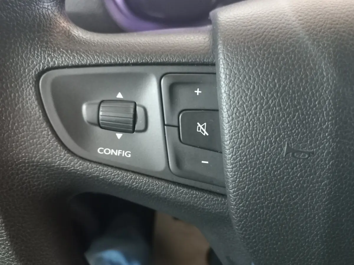 Gros plan sur les commandes du volant noir du Peugeot Traveller gris clair, boutons de configuration et volume visibles.