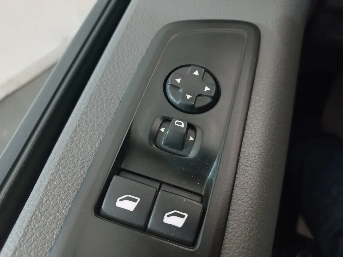 Gros plan sur les commandes de réglage des rétroviseurs et des vitres côté conducteur du Peugeot Traveller gris clair 2021.