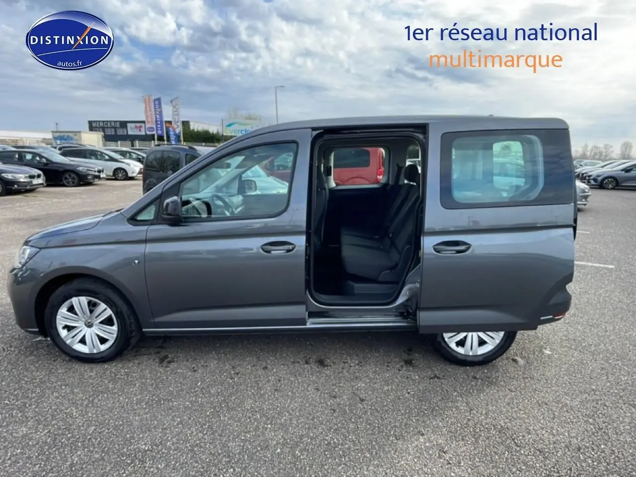 Vue de profil côté gauche d'un Volkswagen Caddy gris indien 2025 avec porte coulissante arrière ouverte montrant l'intérieur.