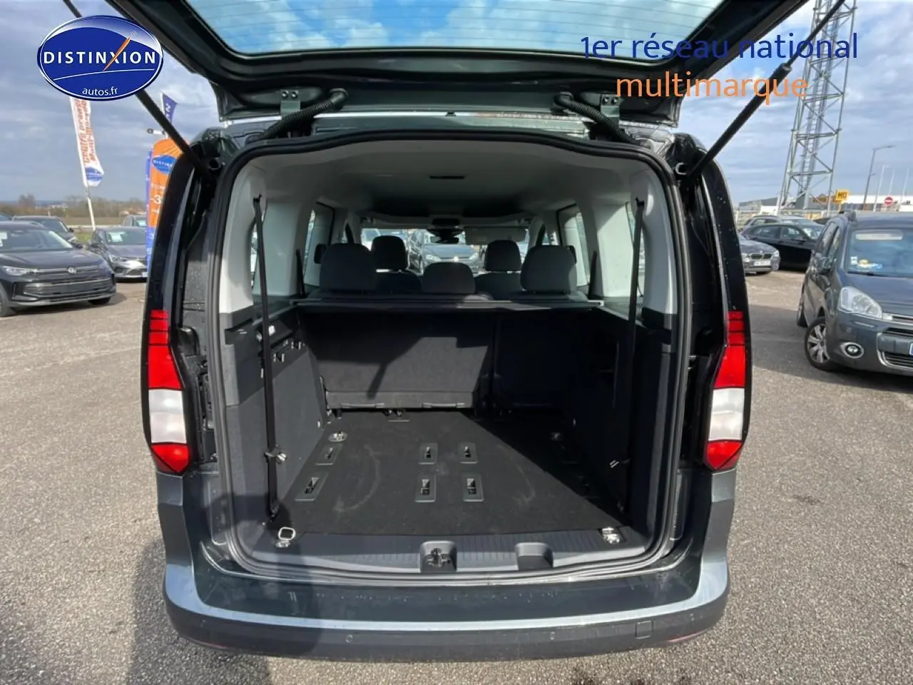 Vue arrière ouverte du Volkswagen Caddy gris indien 2025 montrant le grand espace de chargement et les sièges arrière.