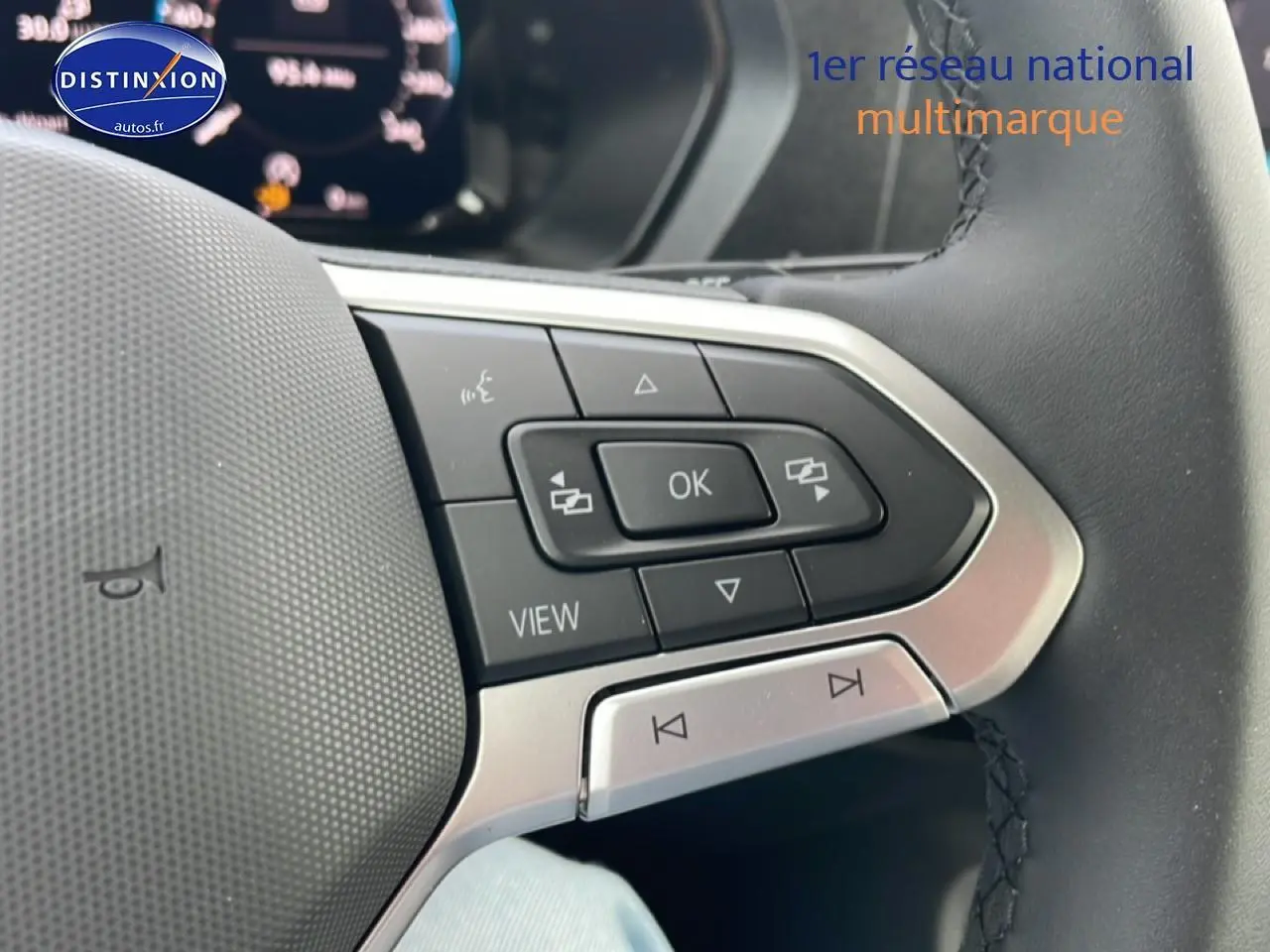 Gros plan sur les commandes multifonctions du volant cuir du Volkswagen Caddy 2025, version 2.0 TDI gris indien.