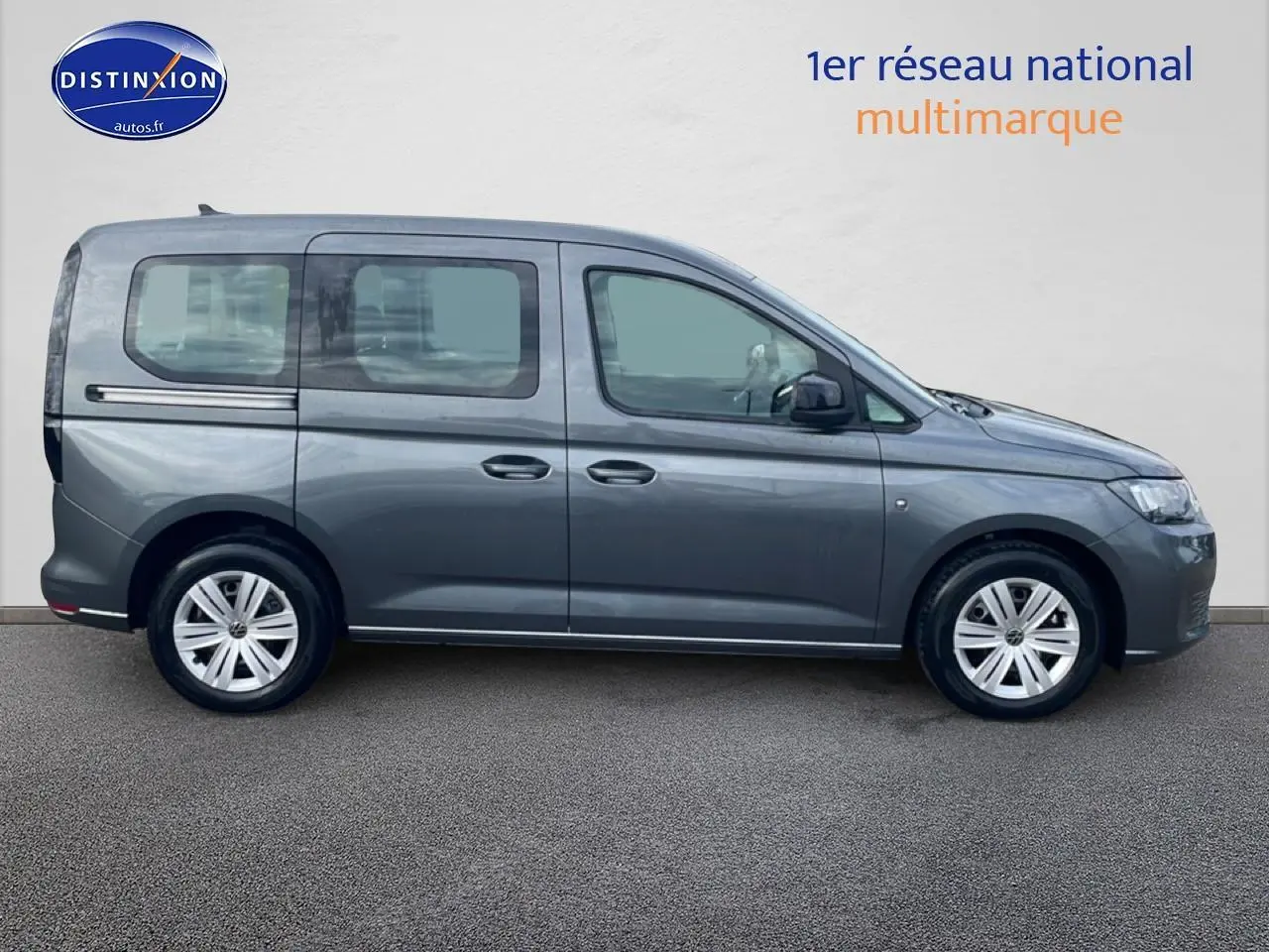 Vue de profil côté gauche d'un Volkswagen Caddy gris indien 2025 sur fond neutre, avec jantes alliage visibles.