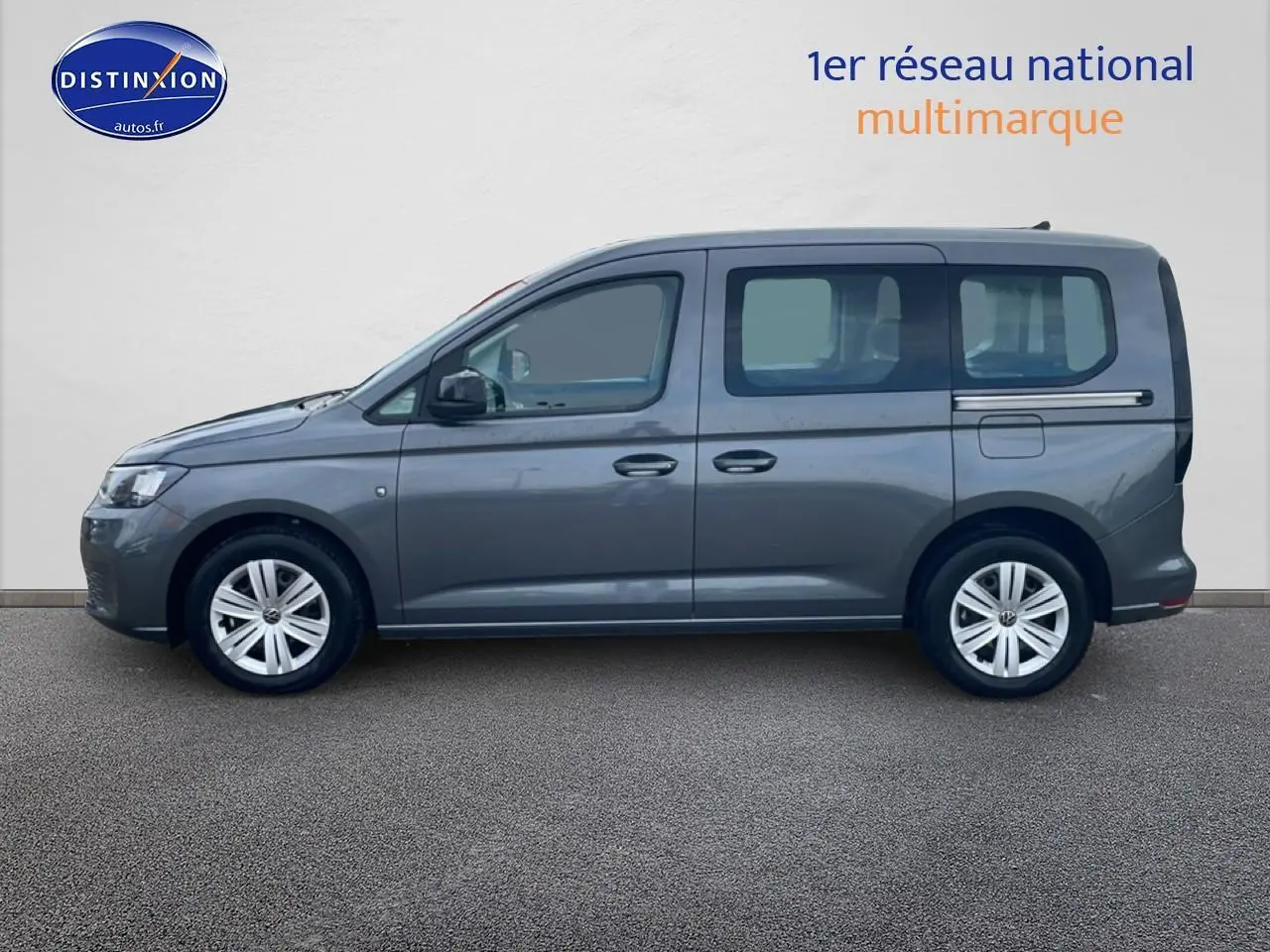 Vue de profil côté gauche d'un Volkswagen Caddy gris indien 2025 avec vitres arrière teintées et jantes alliage.