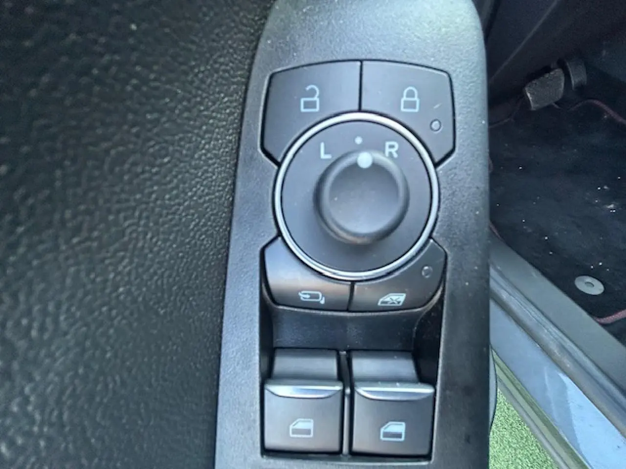 Gros plan sur les commandes de réglage des rétroviseurs et vitres côté conducteur d’un Ford Puma gris Magnetic.