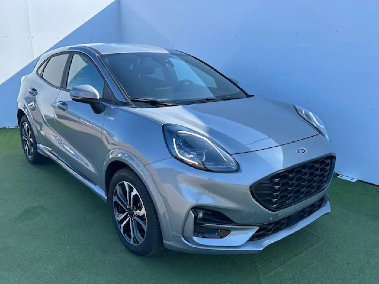 Ford Puma gris Magnetic en vue 3/4 avant droit, avec calandre noire et jantes alliage 17 pouces distinctives.