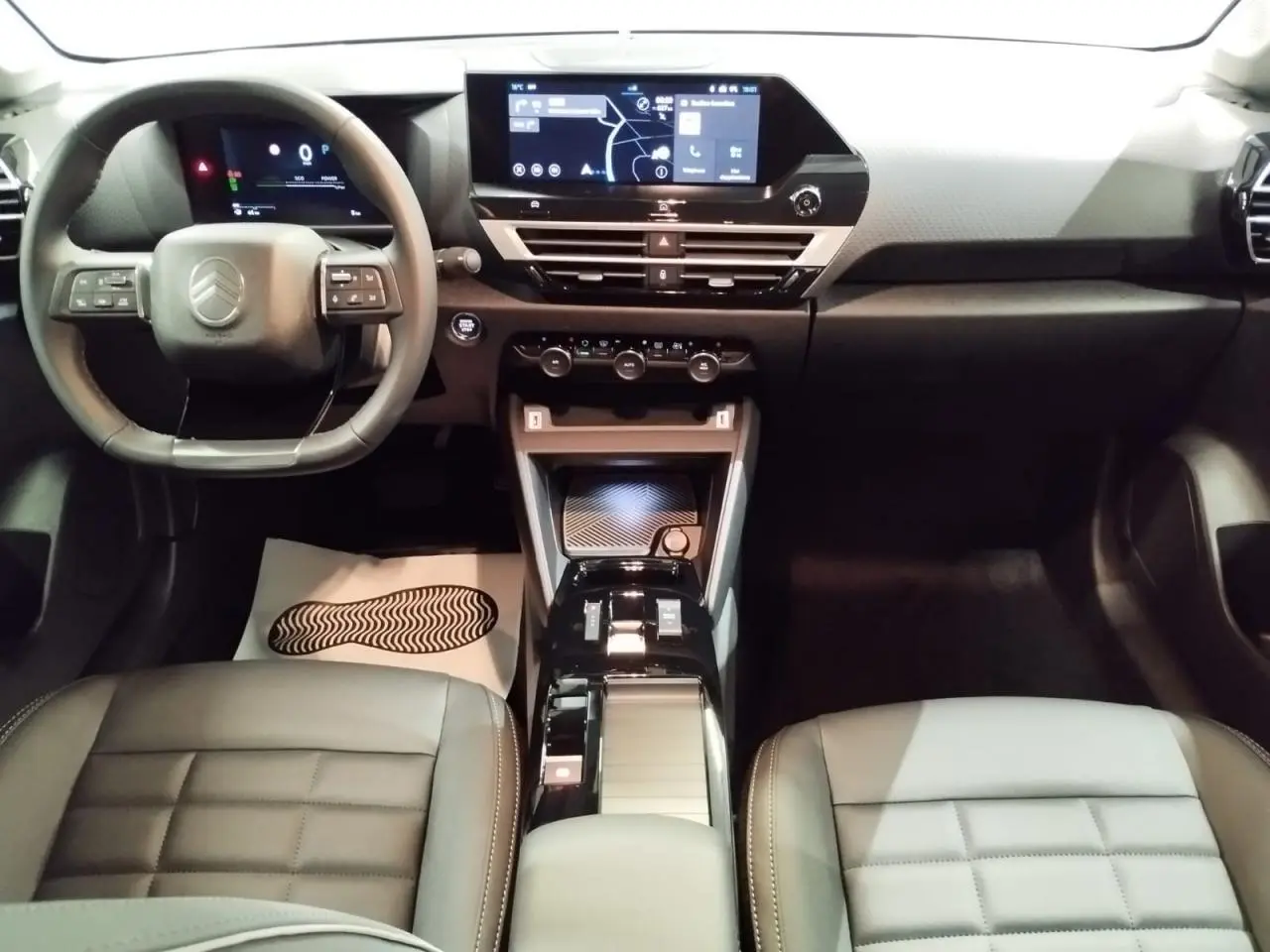 Intérieur avant de la Citroën C4 hybride 2025, vue du tableau de bord et console centrale noire avec écran tactile.