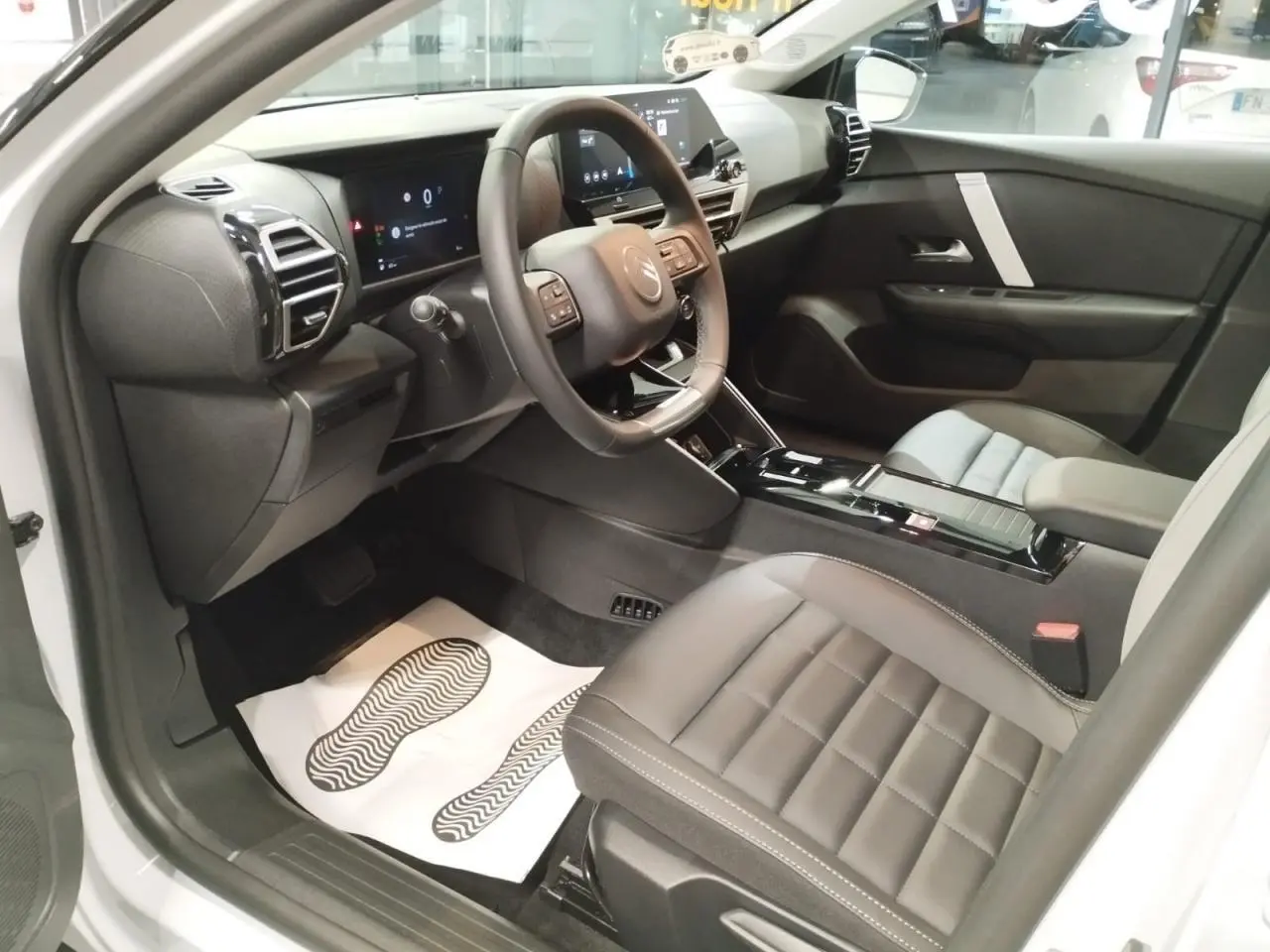 Intérieur avant droit de la Citroën C4 2025, sièges cuir gris, tableau de bord numérique et console centrale noire brillante.