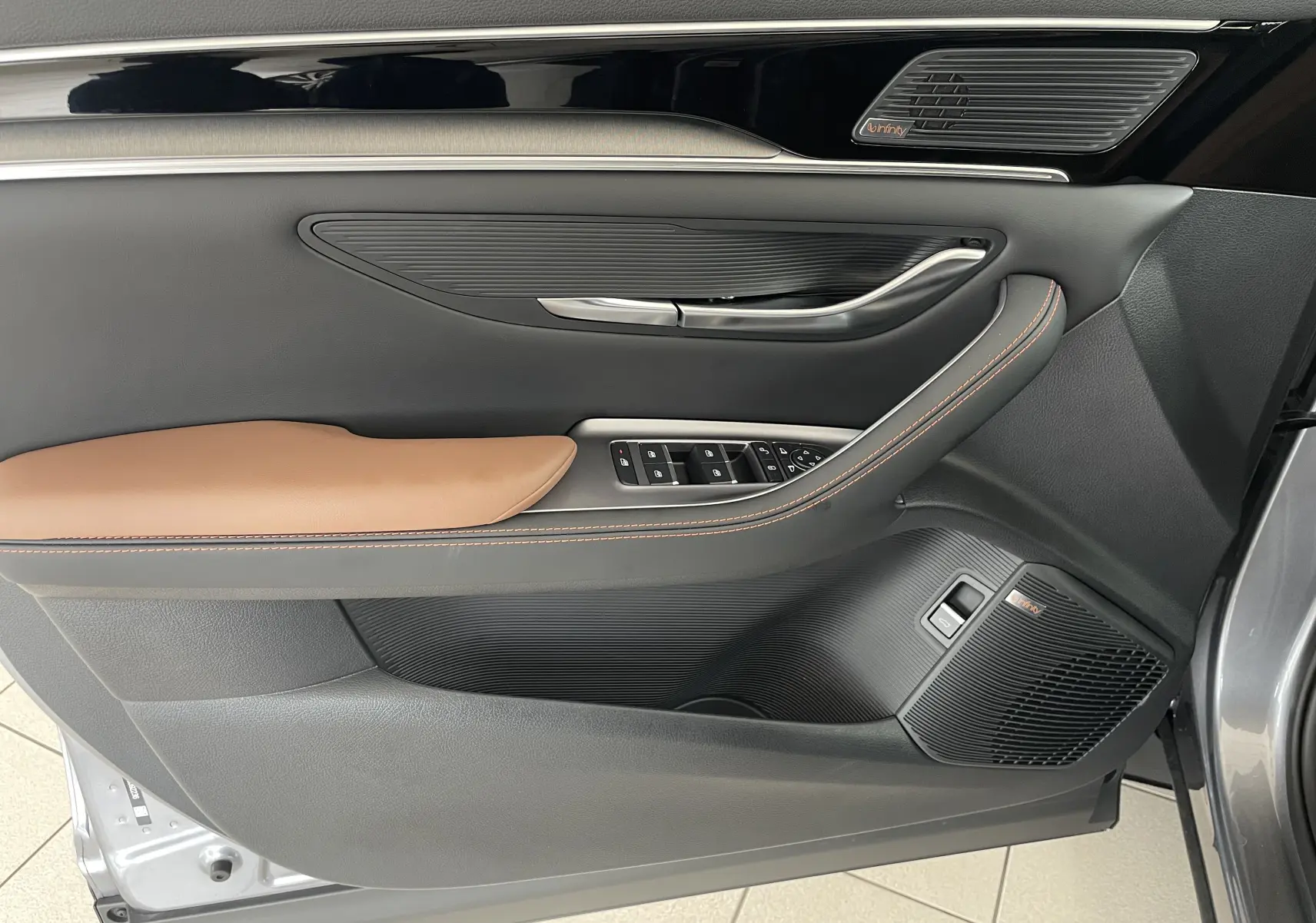 Vue rapprochée de la porte avant gauche du BYD SEAL U 2025 en TIME GREY, avec garniture marron et haut-parleurs Infinity intégrés.