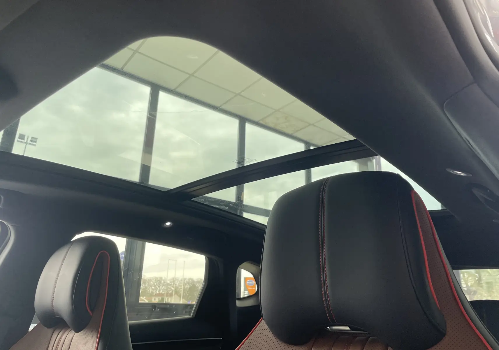 Vue intérieure du toit ouvrant panoramique et des sièges avant en similicuir noir et marron avec surpiqûres rouges du BYD SEAL U.
