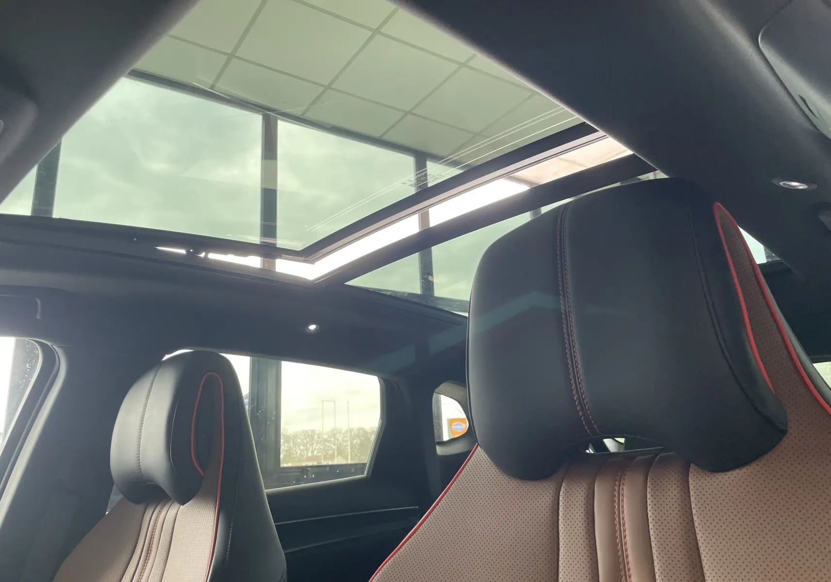 Vue intérieure du toit ouvrant panoramique et des sièges avant en similicuir noir et marron avec surpiqûres rouges du BYD SEAL U 2025.