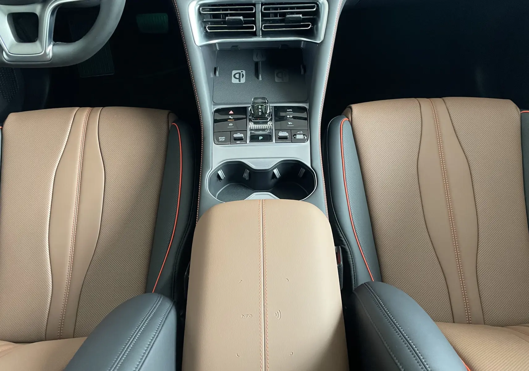 Vue plongeante sur la console centrale et les sièges avant en similicuir brun et noir avec surpiqûres orange du BYD SEAL U 2025.