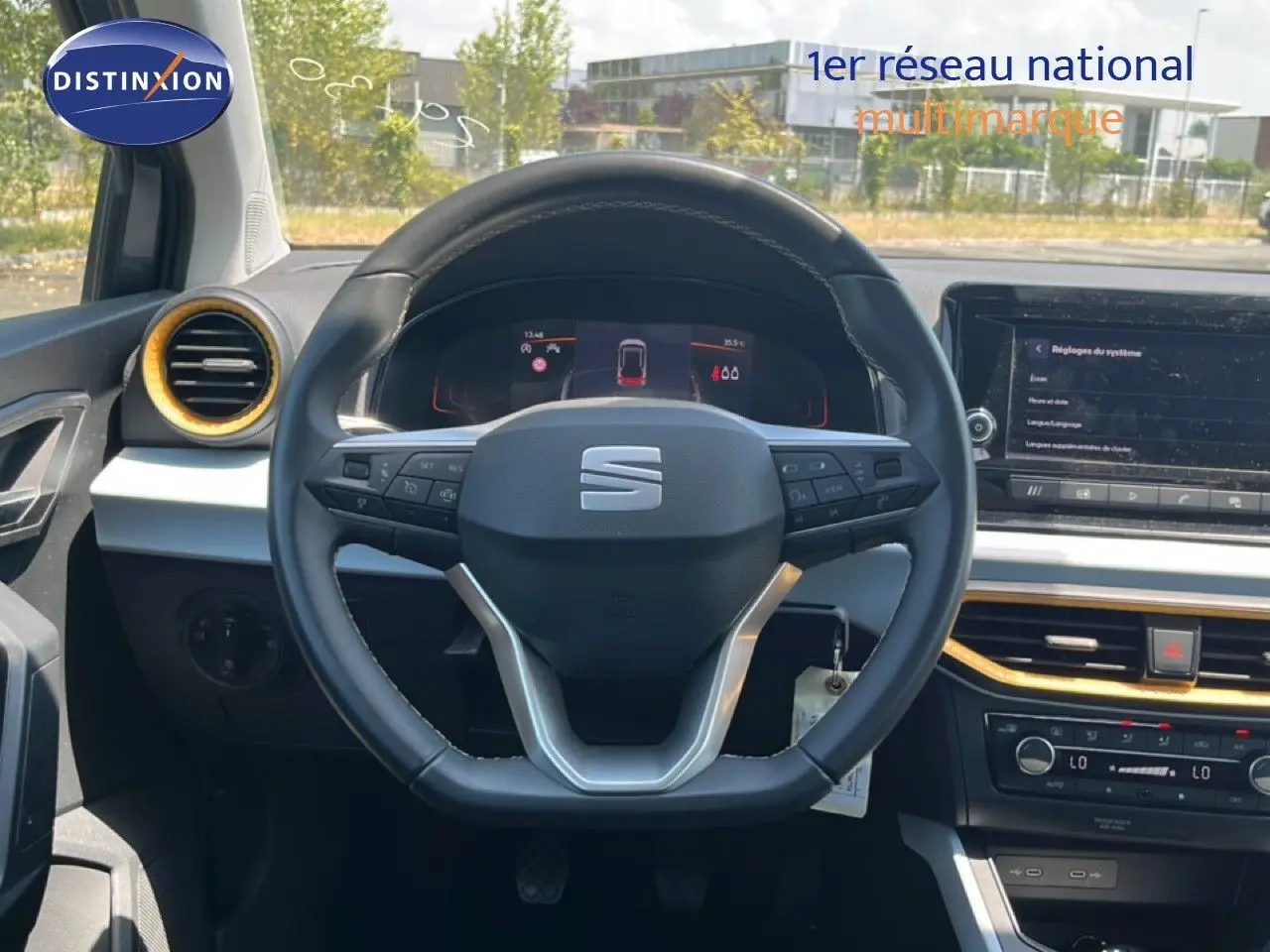 Vue intérieure centrée sur le volant cuir et tableau de bord du SEAT Arona gris avec détails dorés autour des aérateurs.