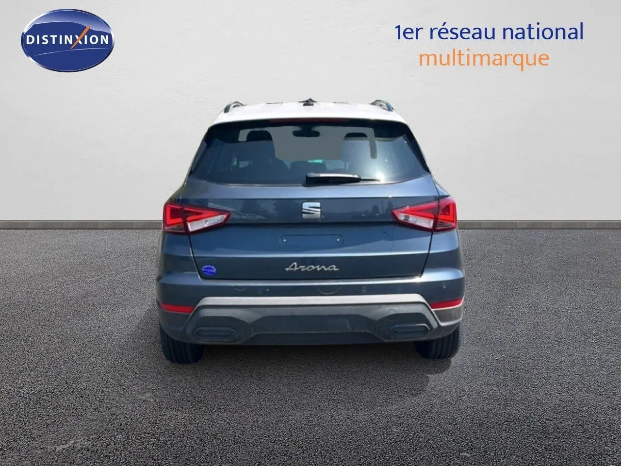 Vue arrière d'un SEAT Arona gris Magnetic Metal avec toit blanc, feux arrière allumés sur fond neutre.