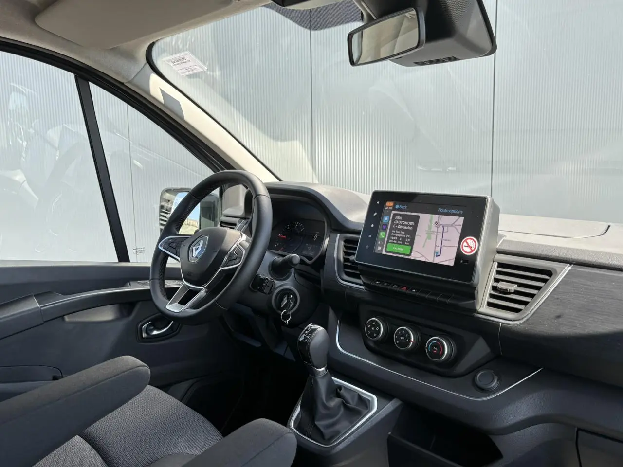 Vue intérieure côté conducteur du Renault Trafic Fourgon gris Urban, avec écran tactile multimédia et volant multifonction.