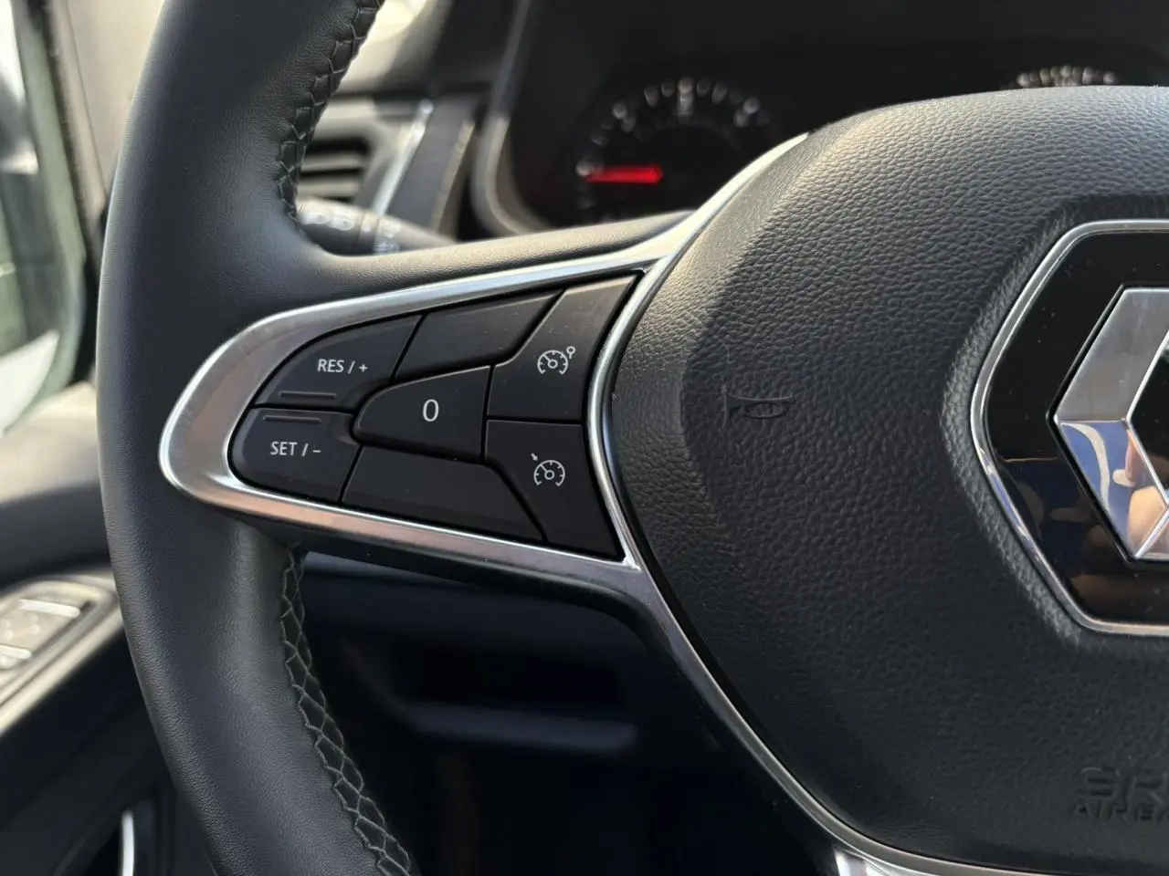 Gros plan sur le volant noir du Renault Trafic Fourgon 2024, mettant en valeur les commandes de régulateur de vitesse.