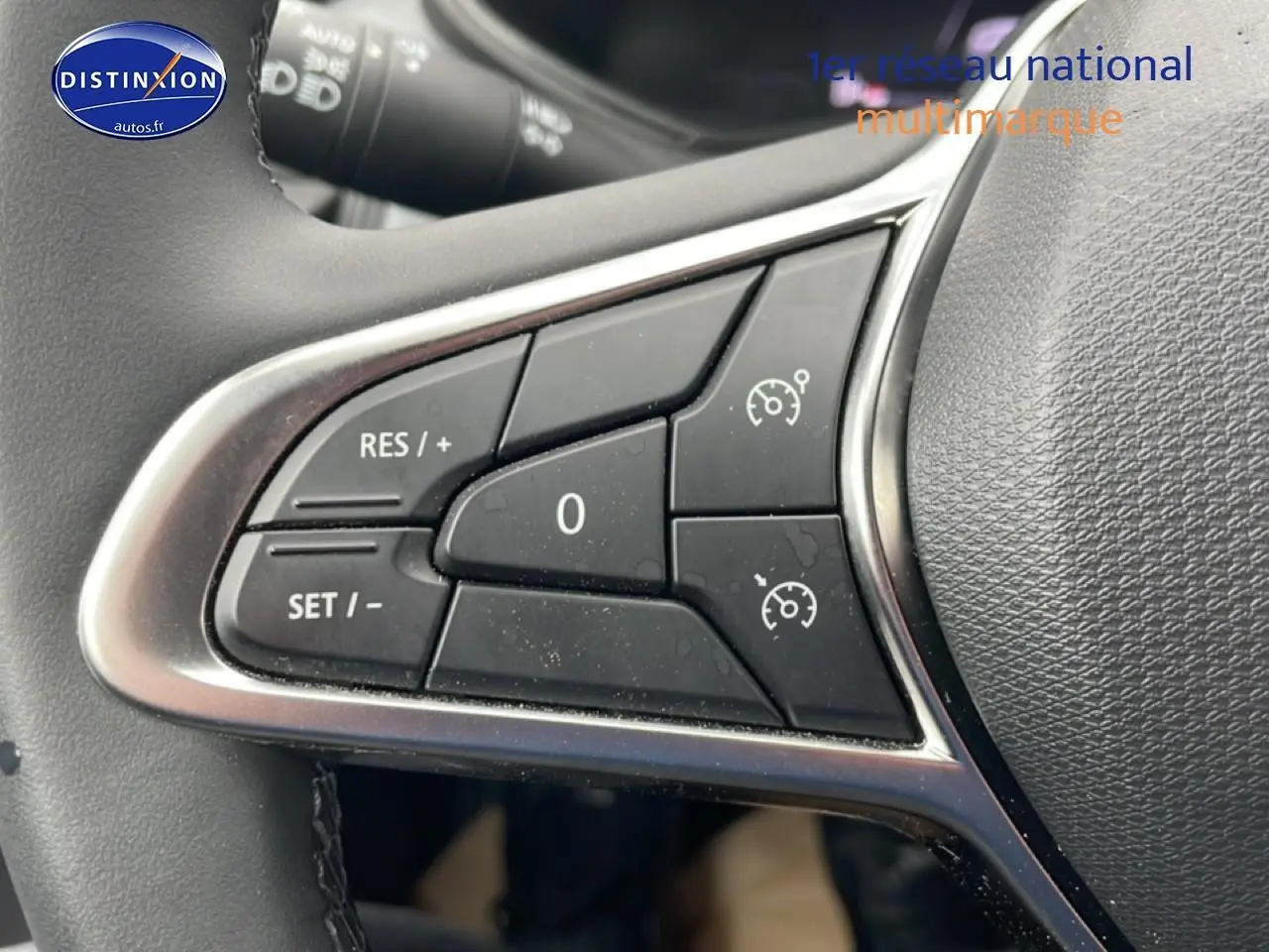 Gros plan sur les commandes du régulateur de vitesse au volant d'une Renault Clio V blanche, version 2025.