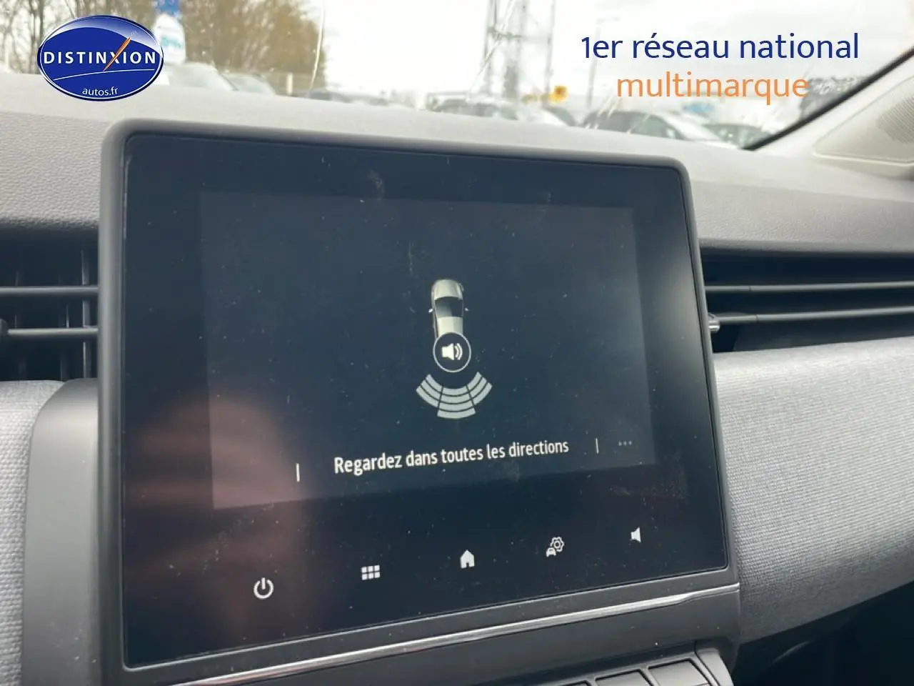 Écran tactile central de la Renault Clio V blanche affichant une alerte de détection d’obstacles, vue intérieure.