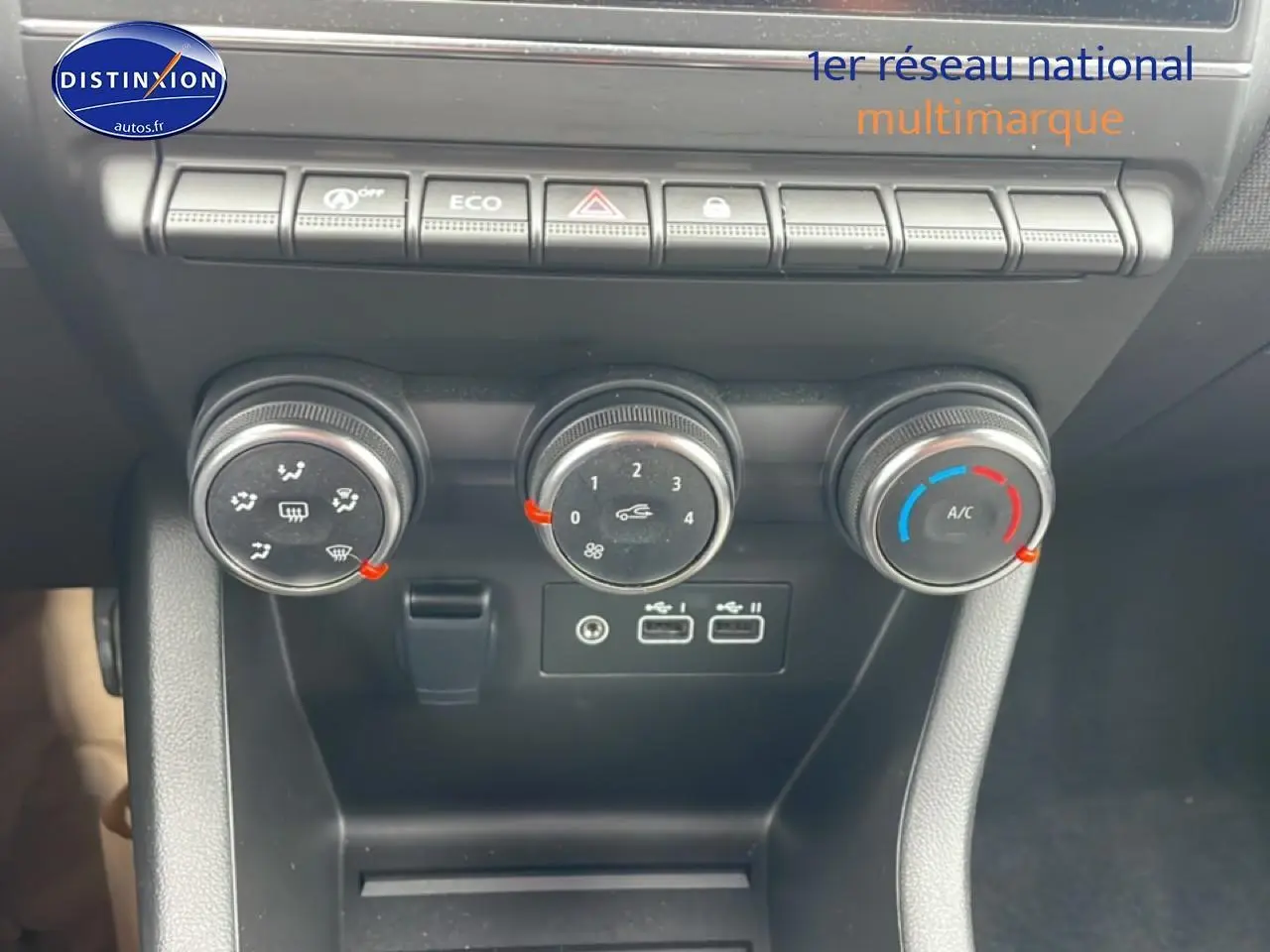 Gros plan sur les commandes de climatisation et les ports USB du tableau de bord de la Renault Clio V blanche.